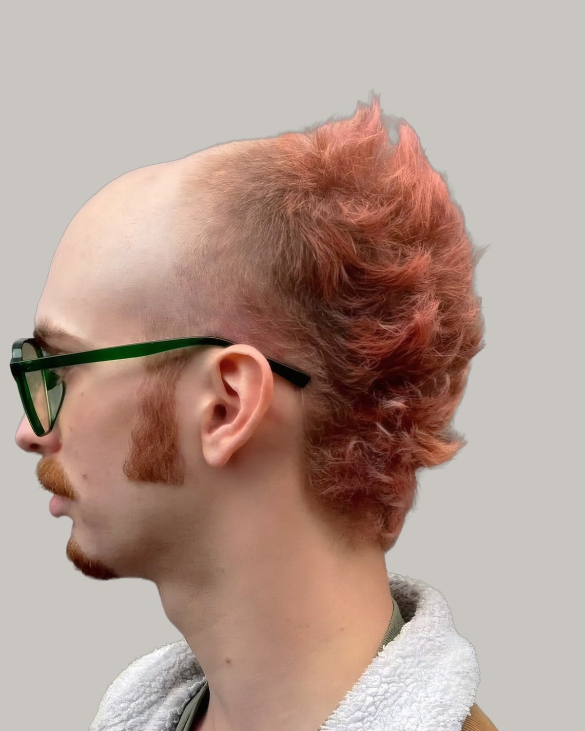 Man with glasses, a bald crown and red hair left long at the sides and back, seen in profile