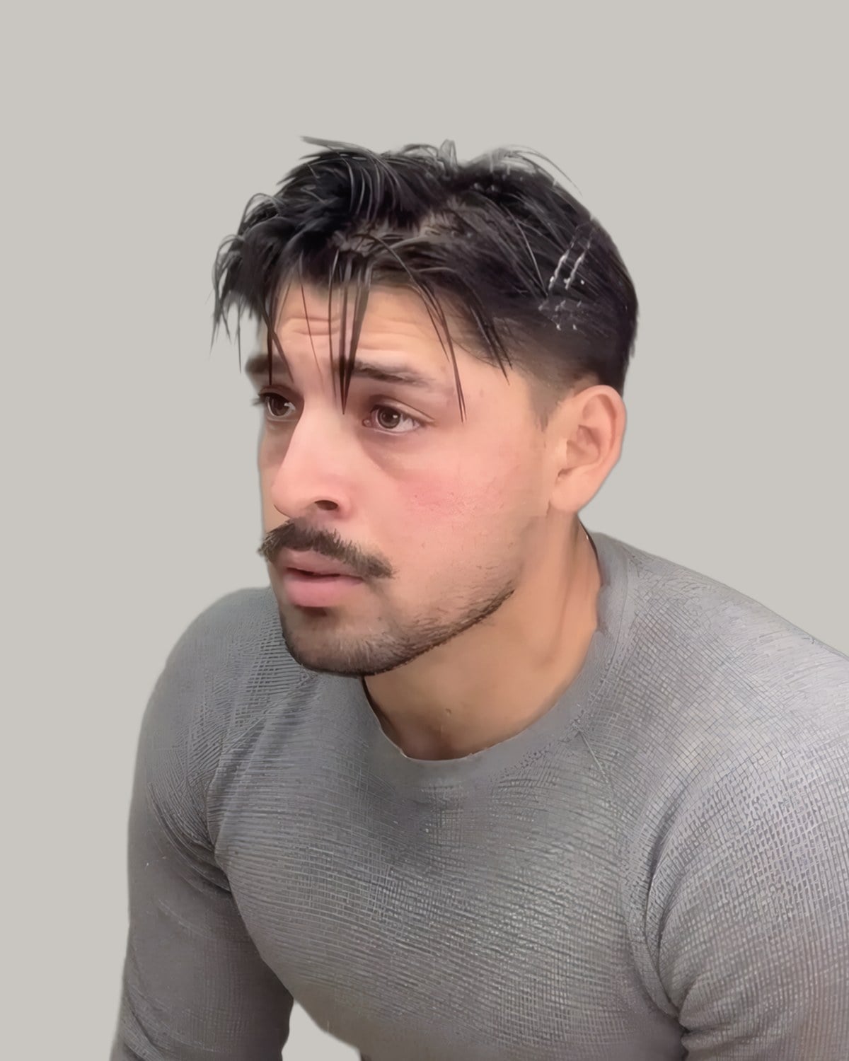 Man in a grey sweater with dark hair swept back over short sides