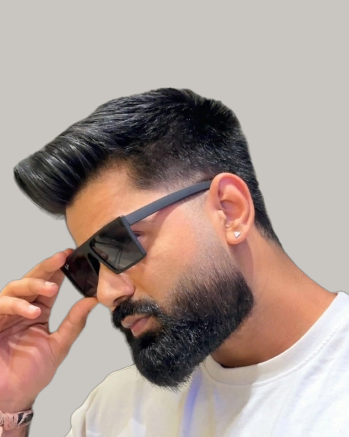 Bearded man in sunglasses with dark hair swept up and back