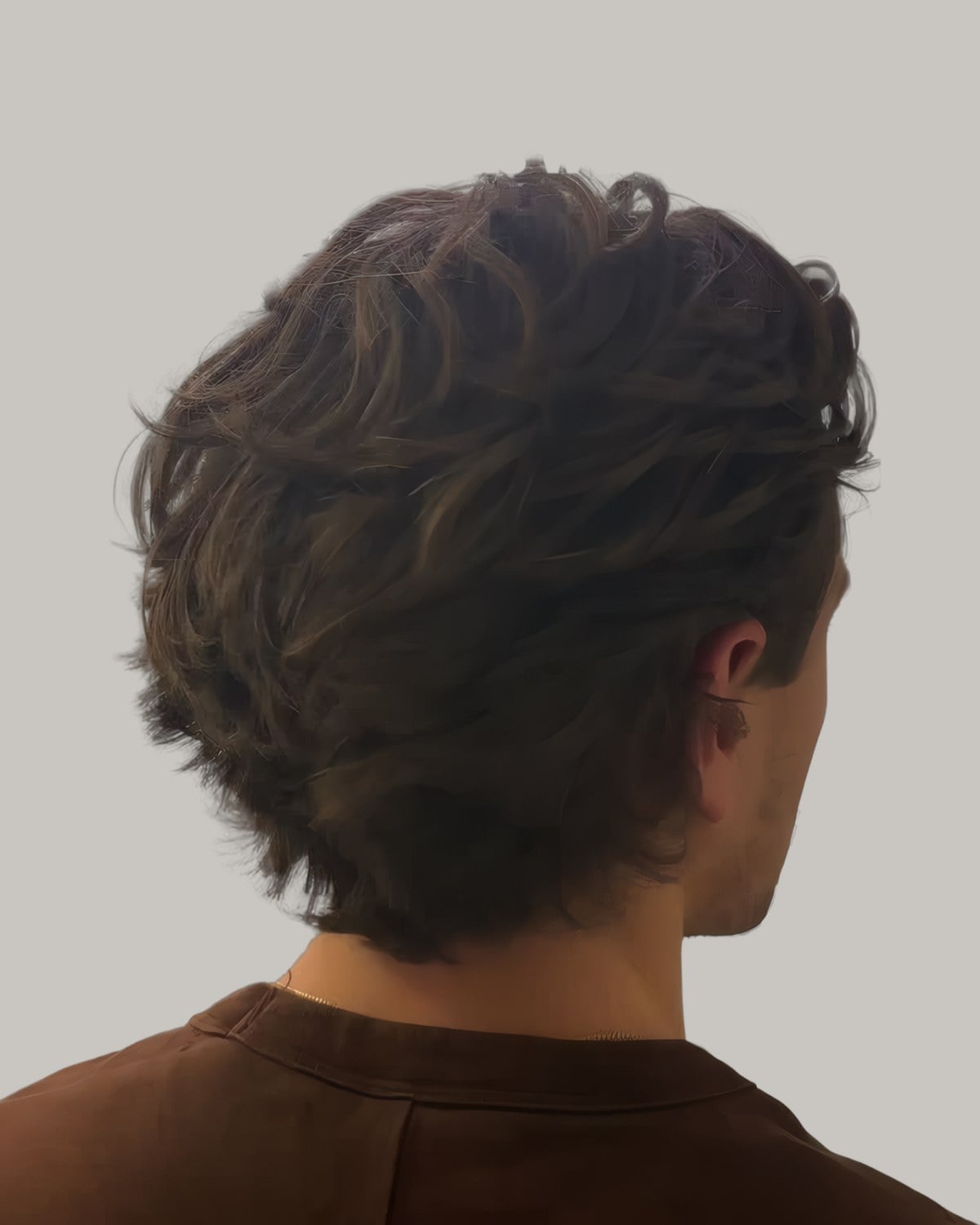 Man with thick, textured brown hair falling in layers to his neck, seen from behind