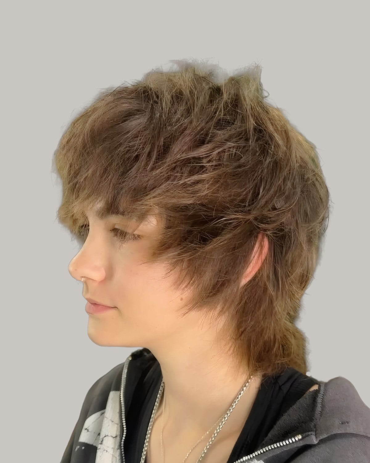 Person with shaggy, layered light brown hair and a long fringe, seen from the side