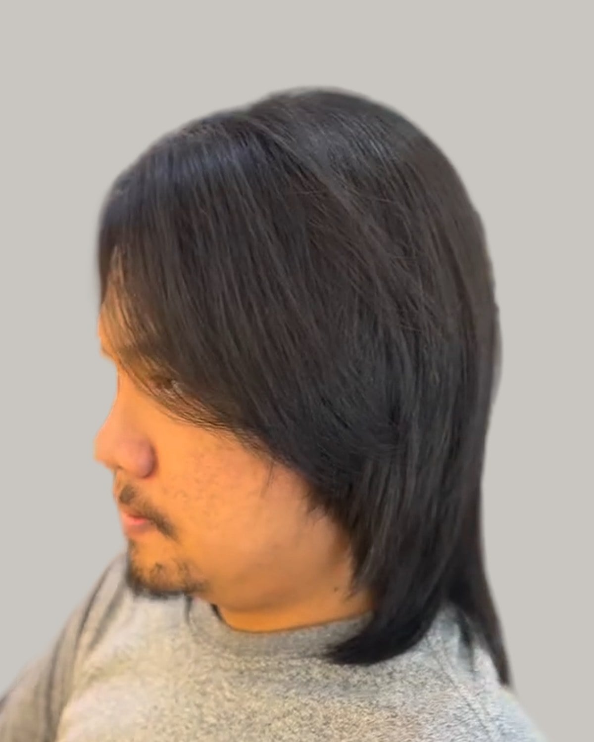 Man with a long, straight layered wolf cut and a goatee, seen in profile
