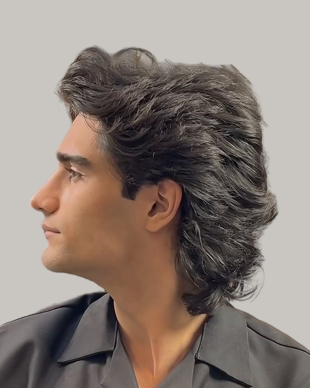 Man with a long, wavy wolf cut, seen from the side at a three-quarter angle