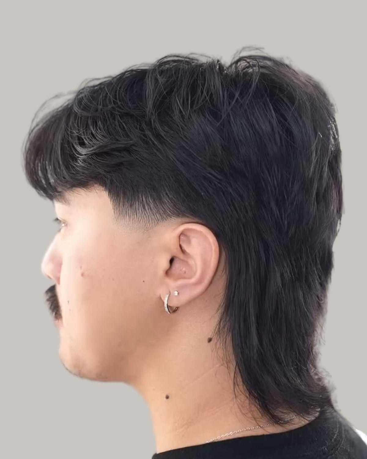 Man with a wolf cut and a taper fade, seen in profile