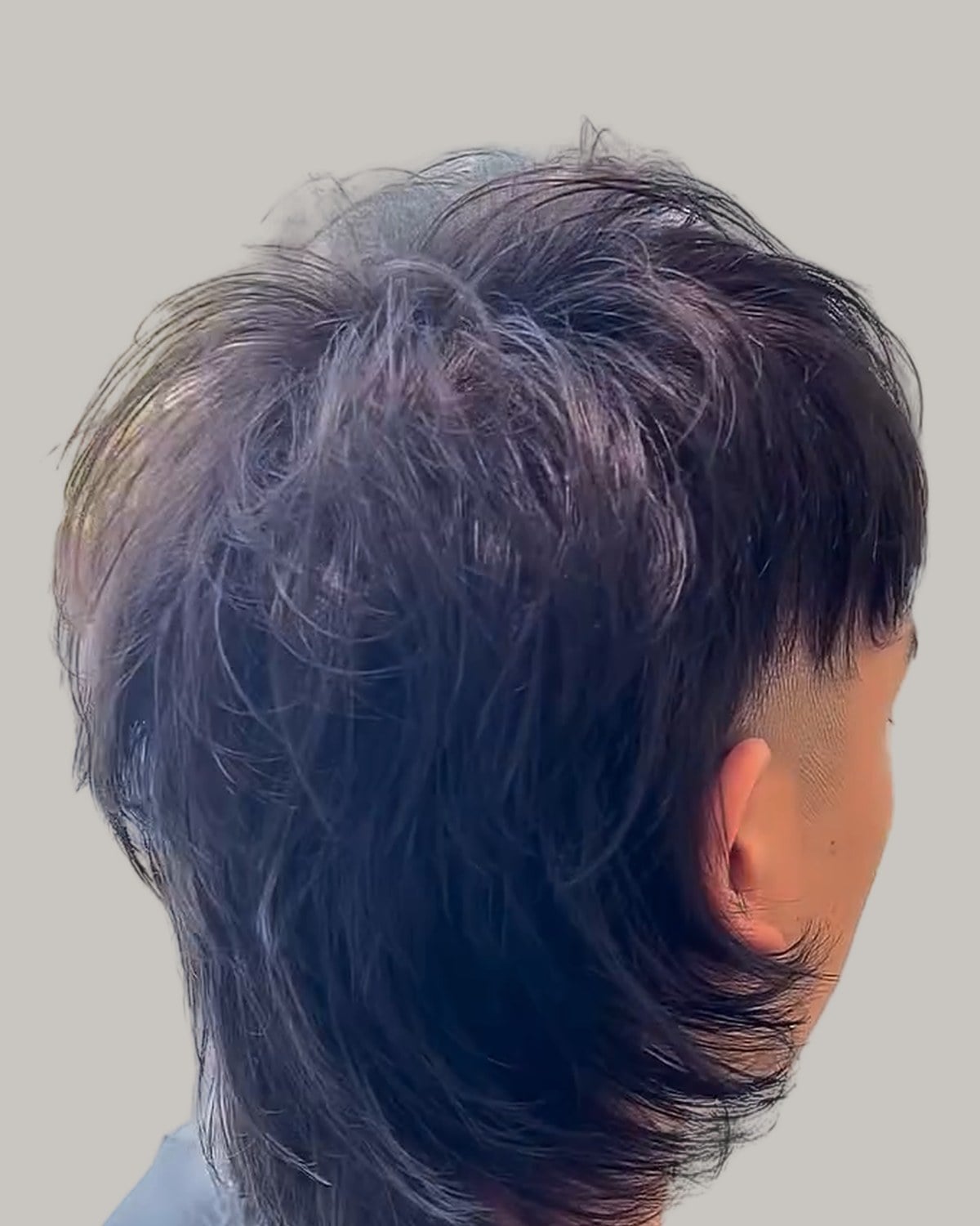 Wolf cut mullet seen from behind at an angle, with the faded side showing