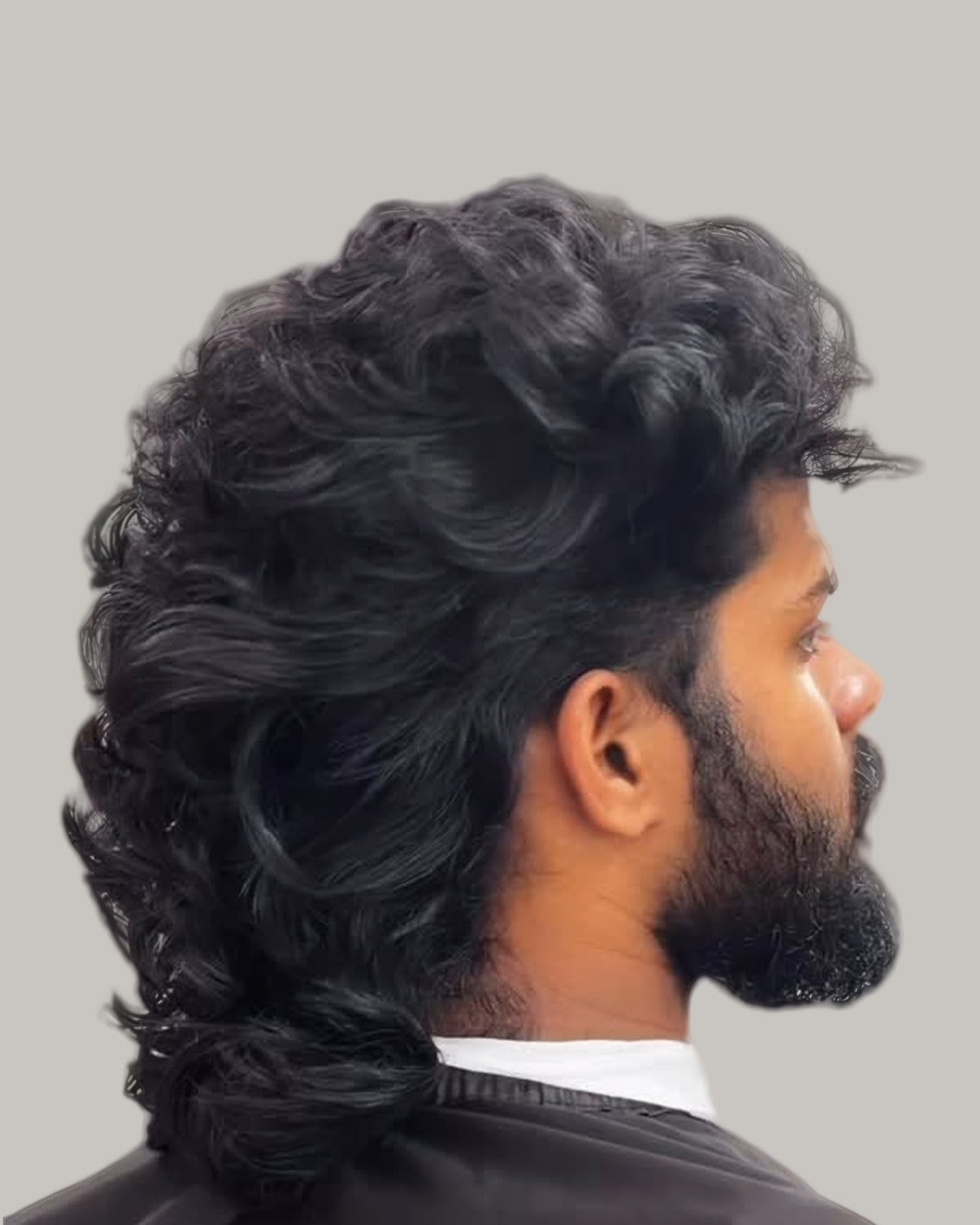 Bearded man with a long curly mullet, seen from behind at an angle