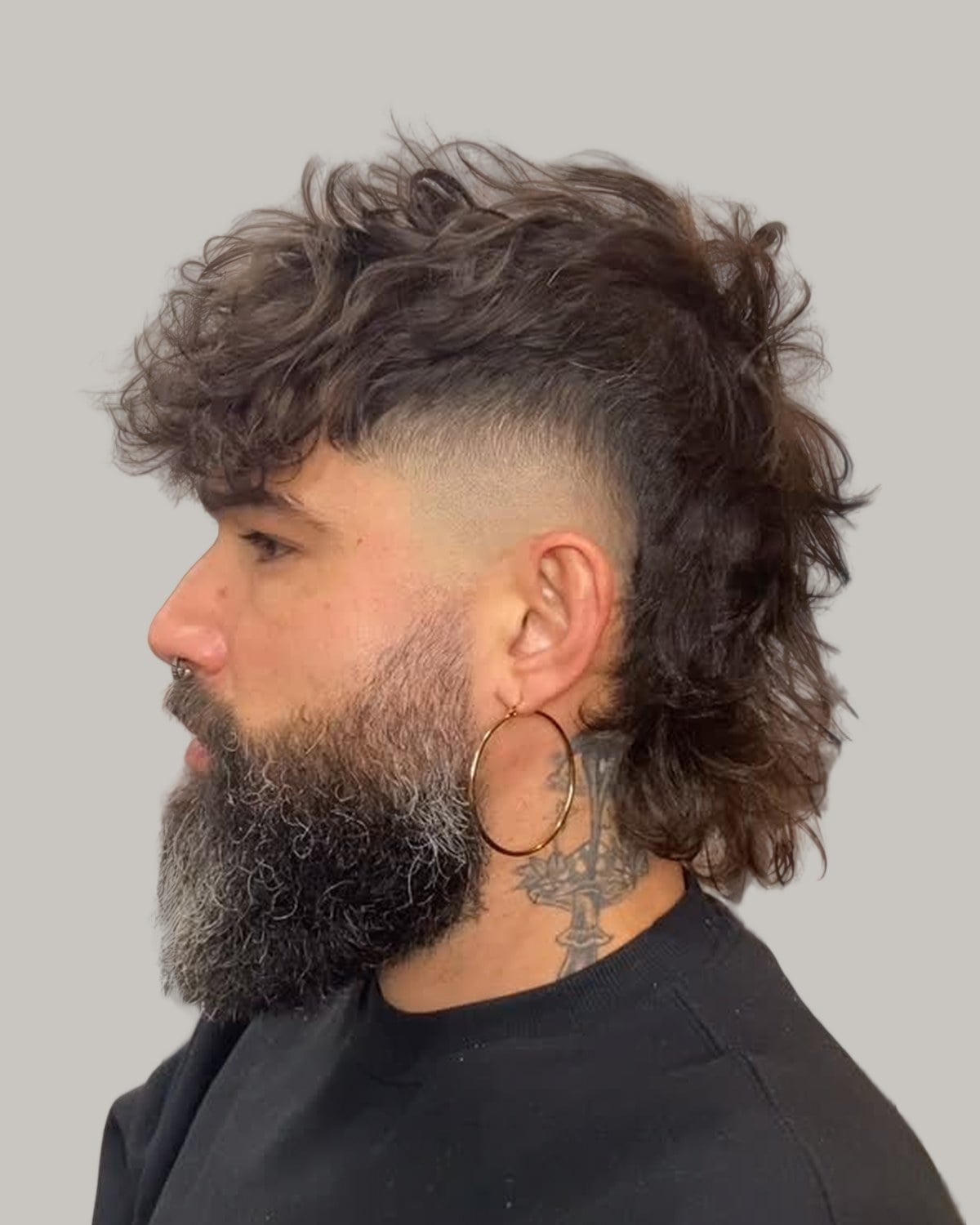 Bearded man with a curly mohawk mullet and faded sides, seen in profile