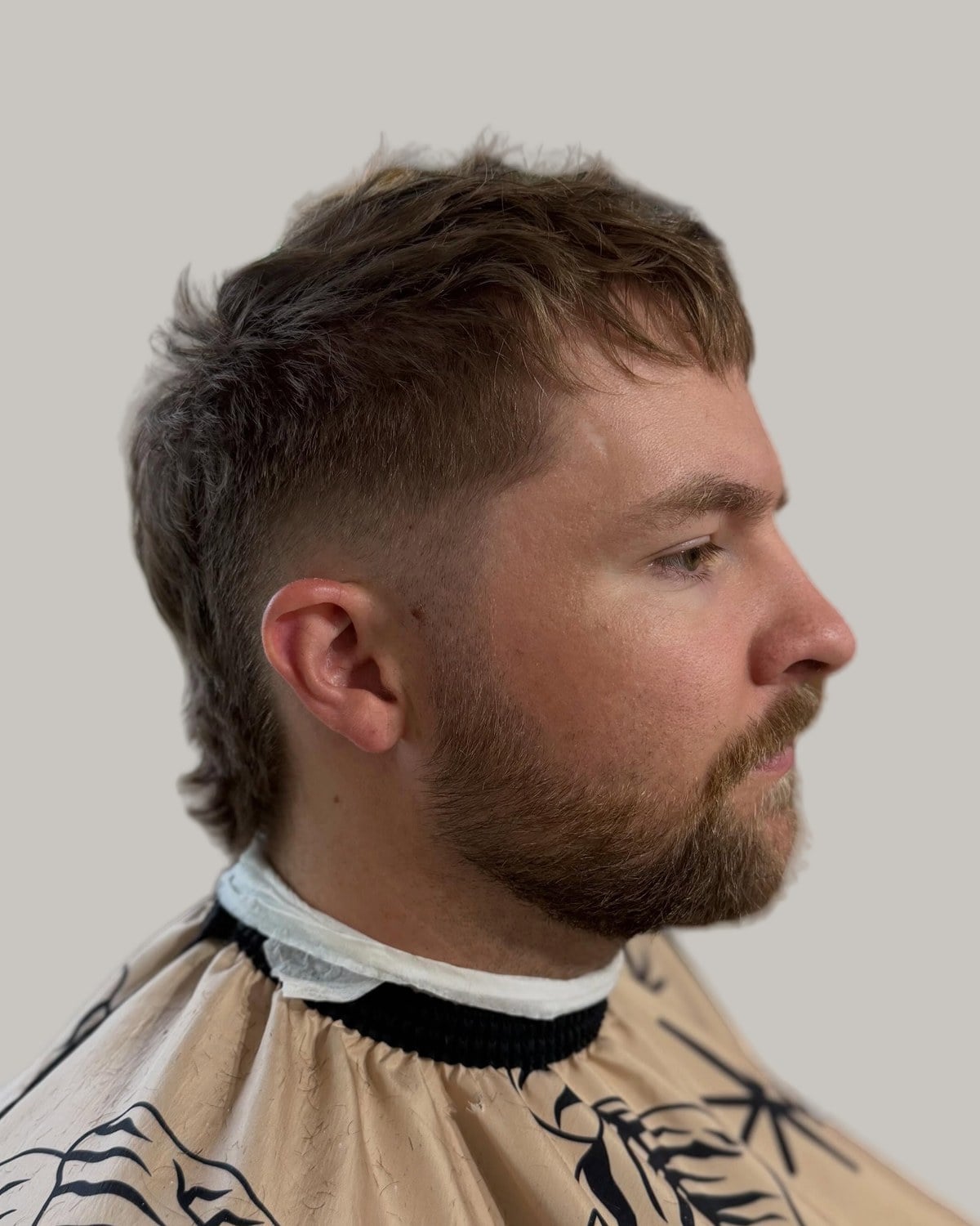 Bearded man with a short textured mullet, seen at an angle