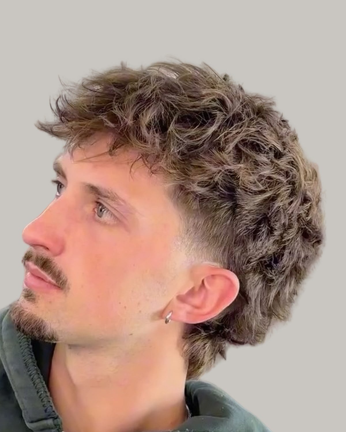 Man with a short curly mullet and a mustache, looking up and to the side