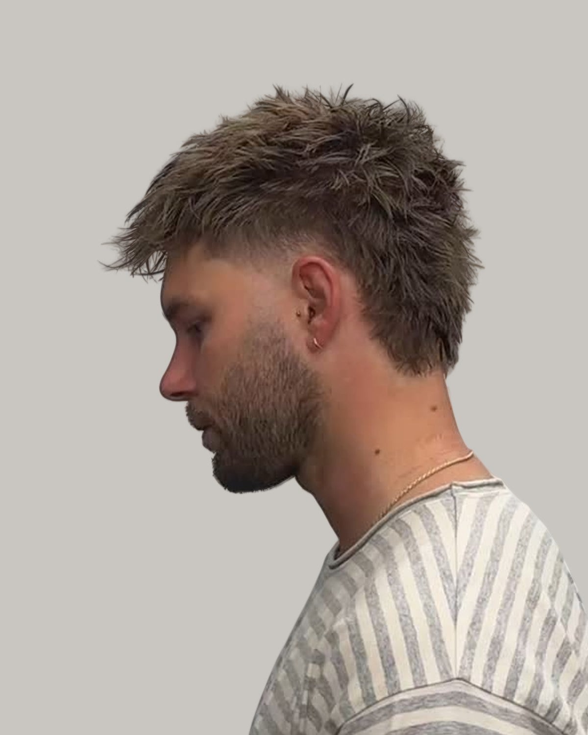 Bearded man with a short, blond-tipped mullet, looking down in profile