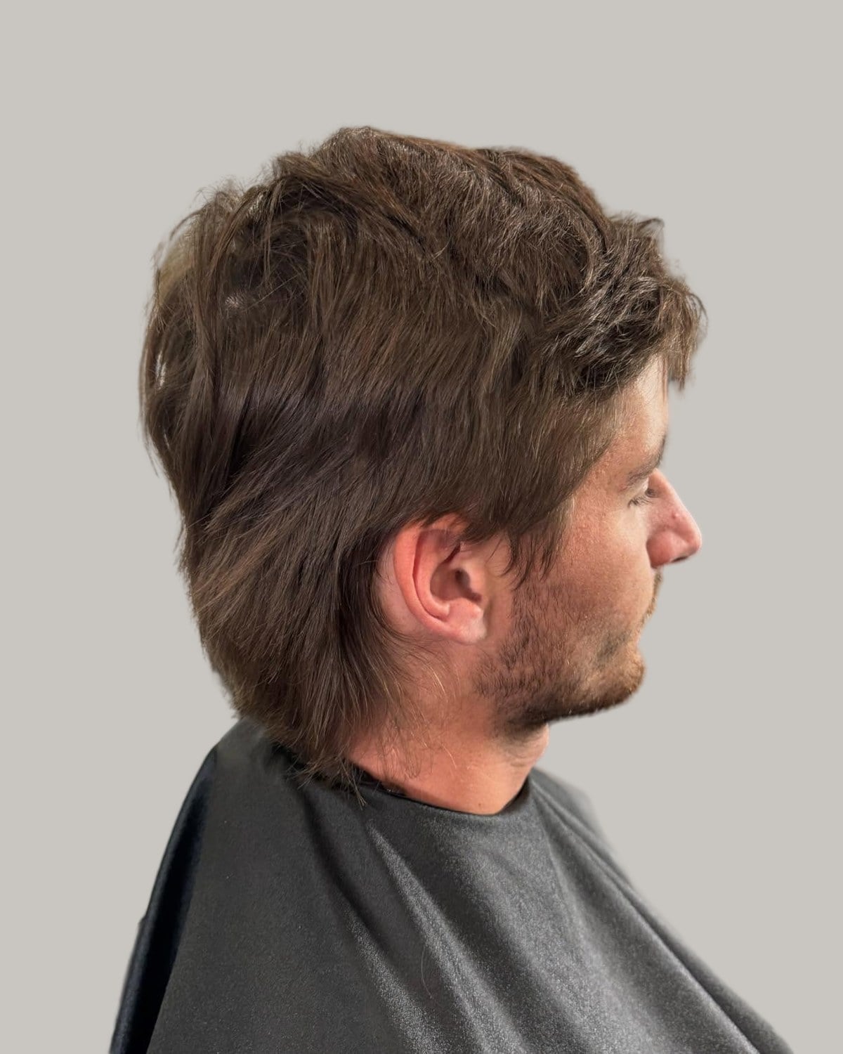 Man with a straight brown mullet, seen from behind at an angle