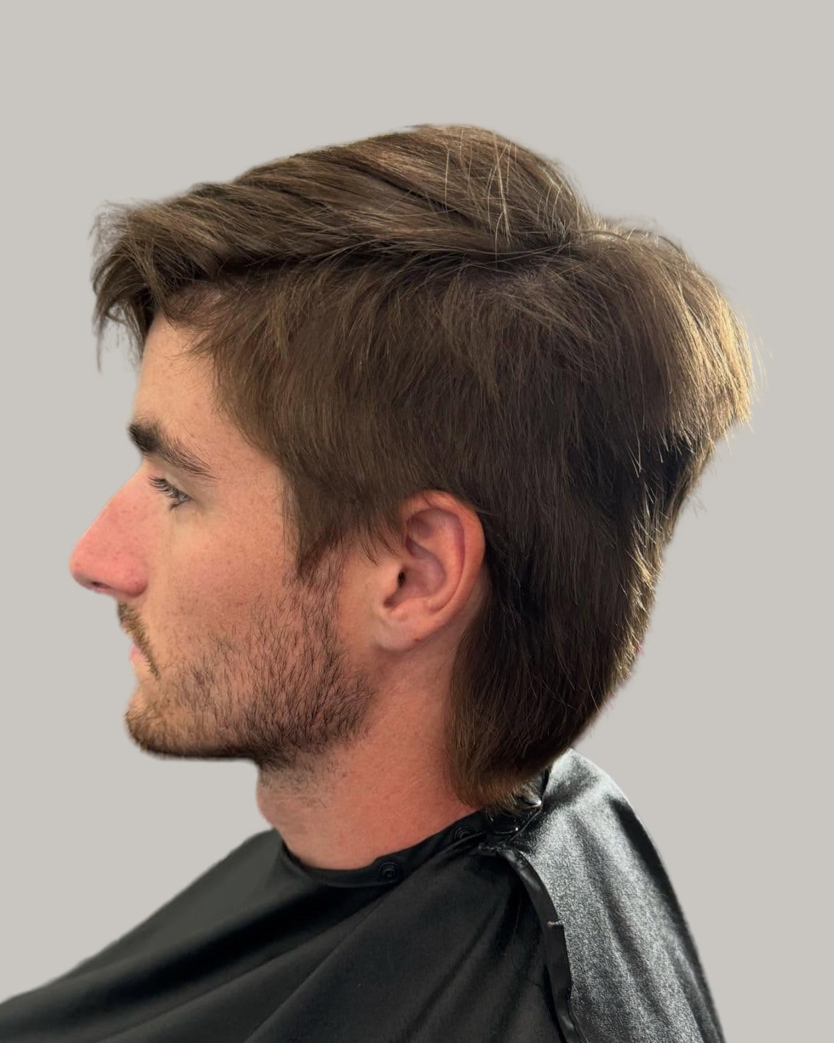 Man with straight brown hair cut into a mullet, seen in profile