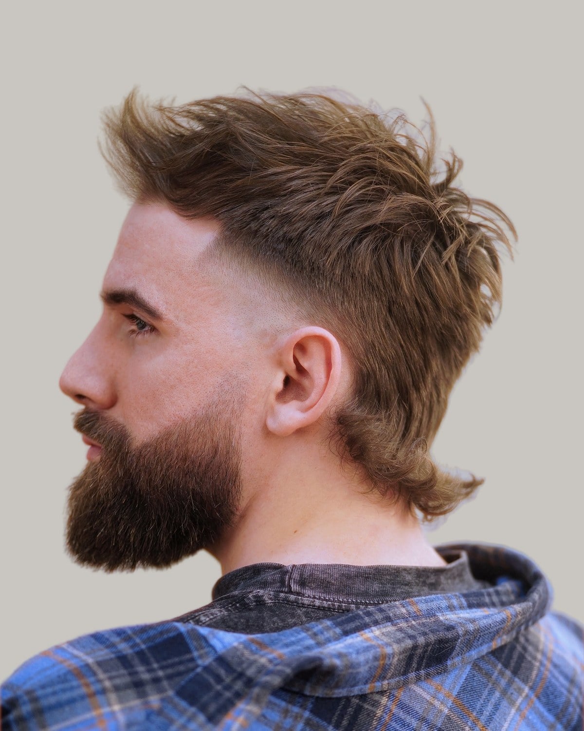 Bearded man with a choppy light brown mullet and a taper fade, seen in profile