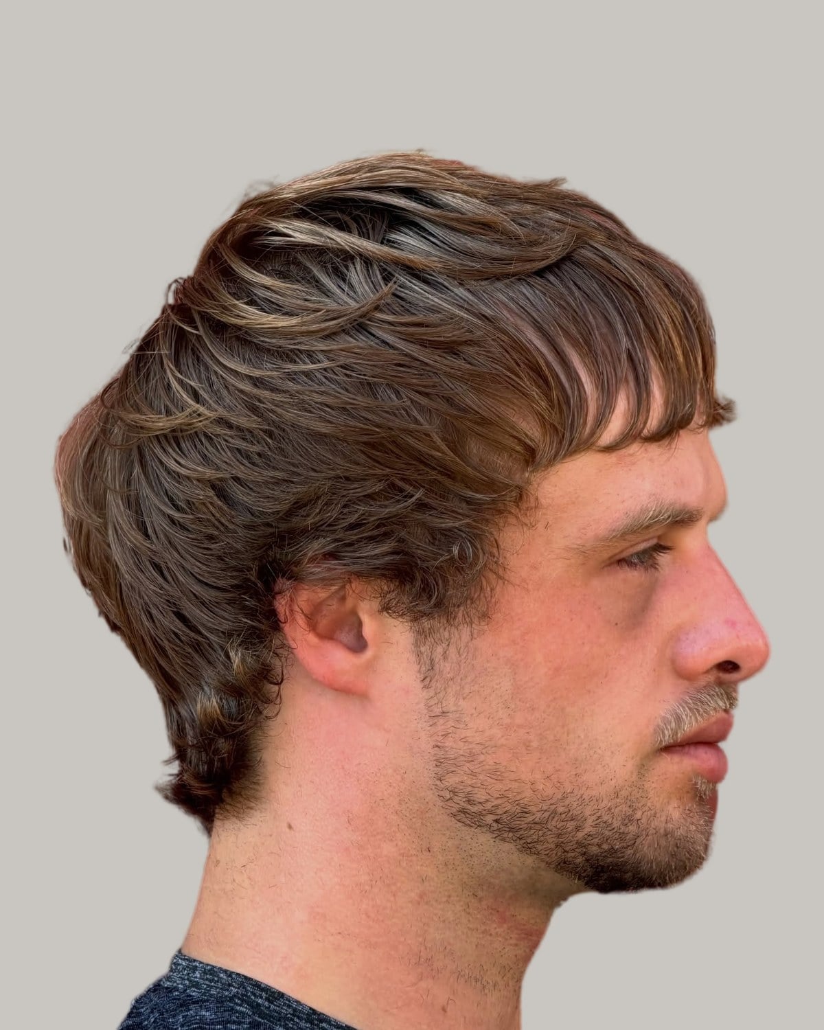 Man with a wavy brown mullet and a fringe, seen in profile
