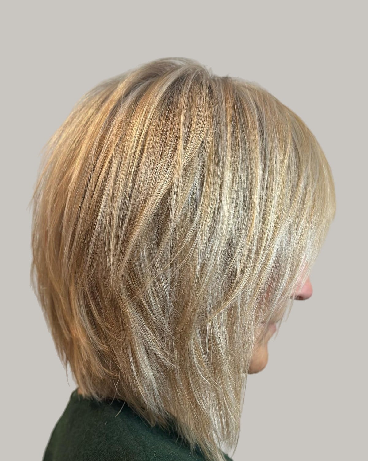 Blonde layered shag seen from behind and to one side, over a green top