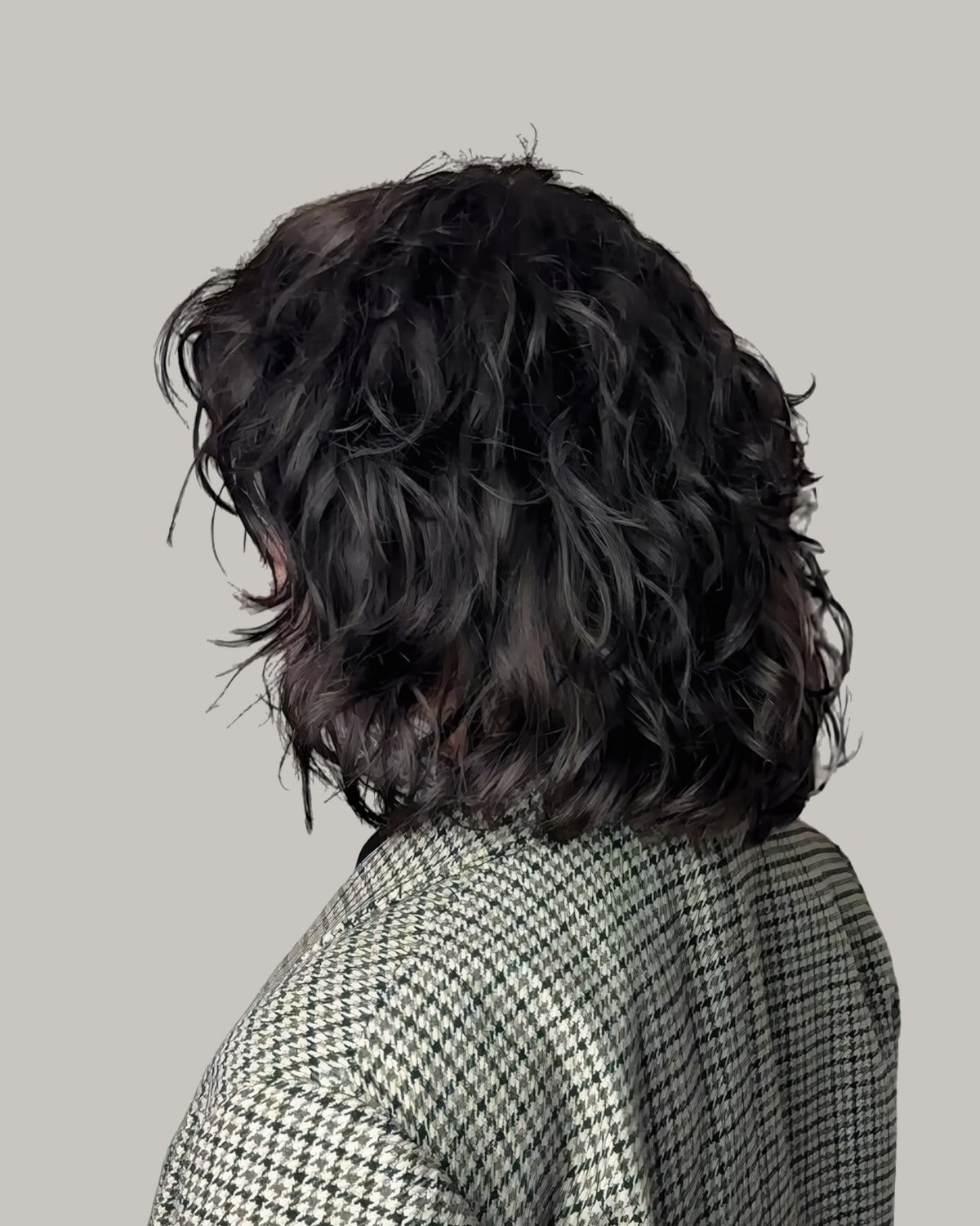 Back view of a jaw-length dark curly shag over a houndstooth blazer