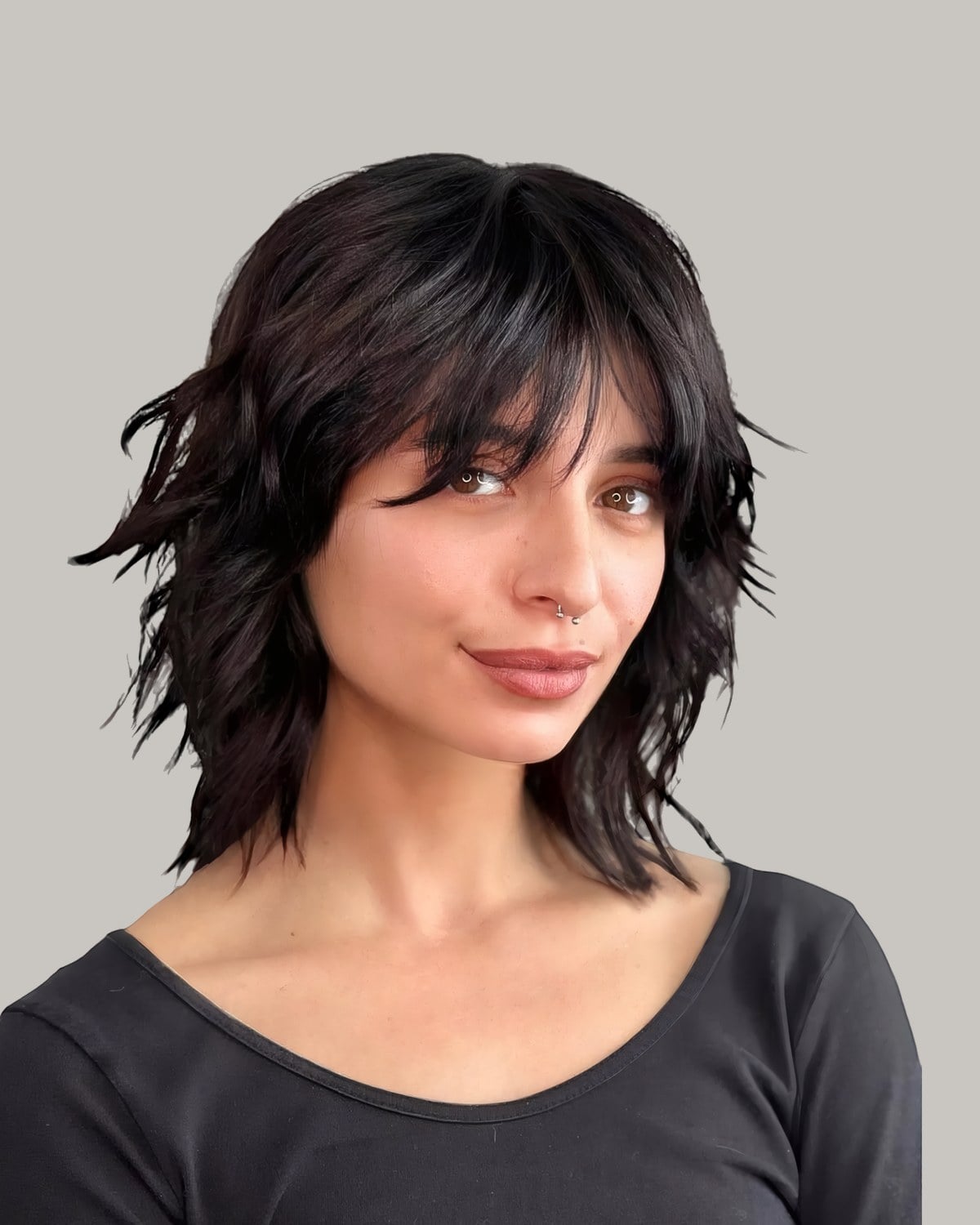 Woman with a black shag and full bangs, seen in three-quarter view