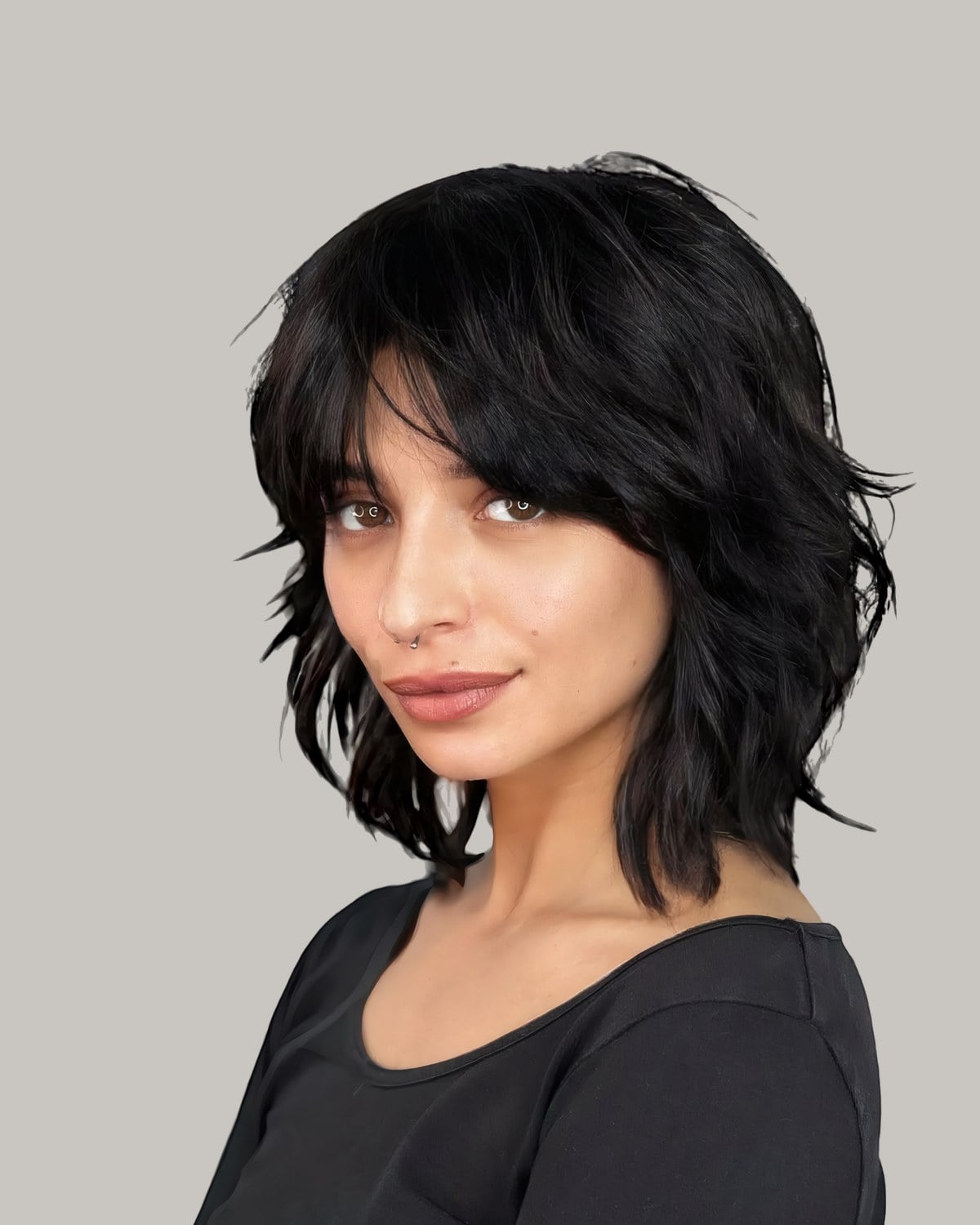 Woman in a dark scoop-neck top with a black shag, split bangs and choppy layers
