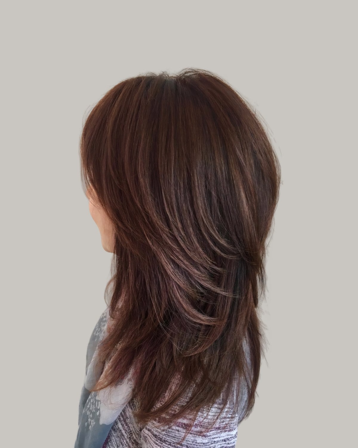 Long auburn-brown hair with feathered layers, seen from behind at an angle