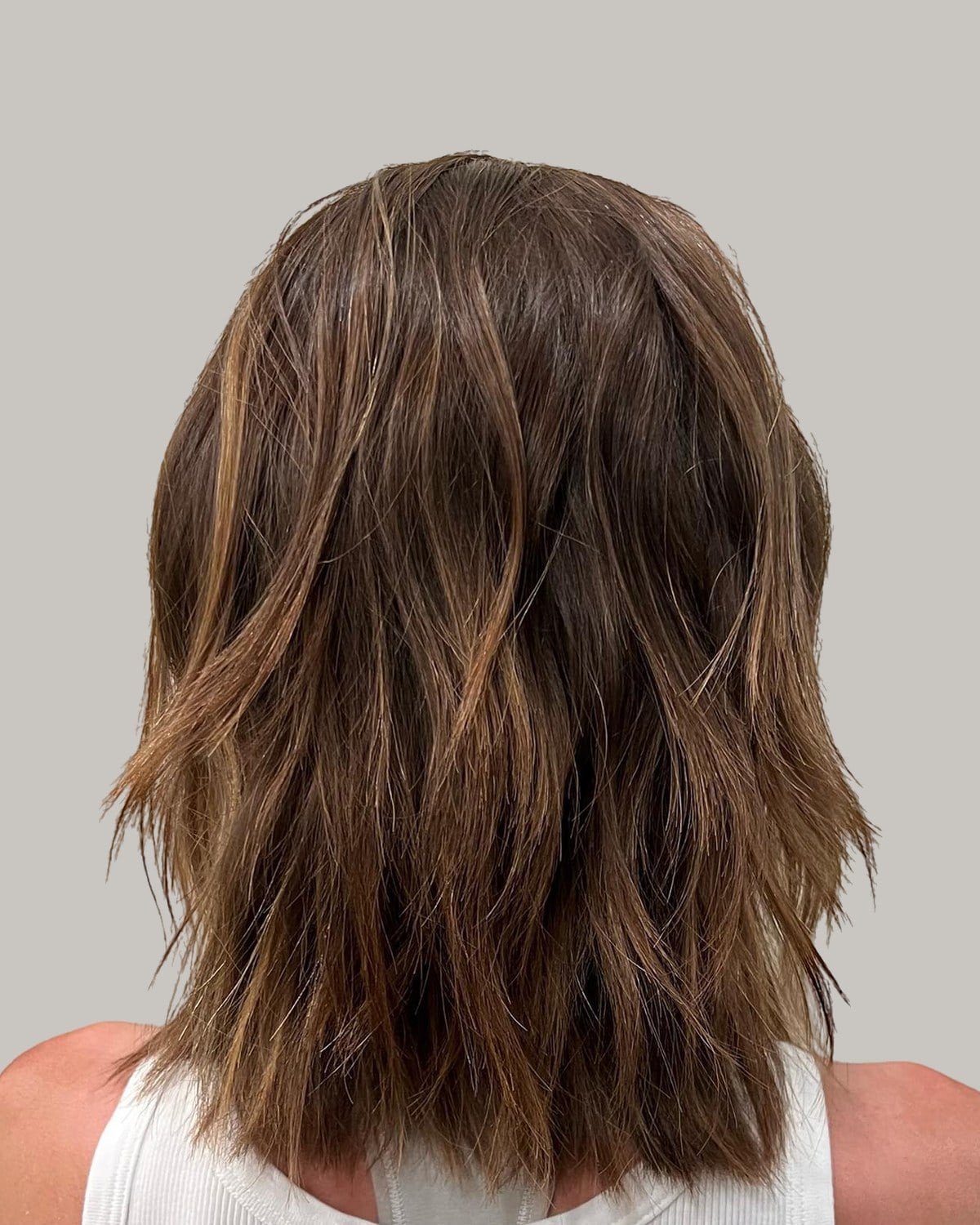 Back view of a brown shaggy lob with caramel highlights