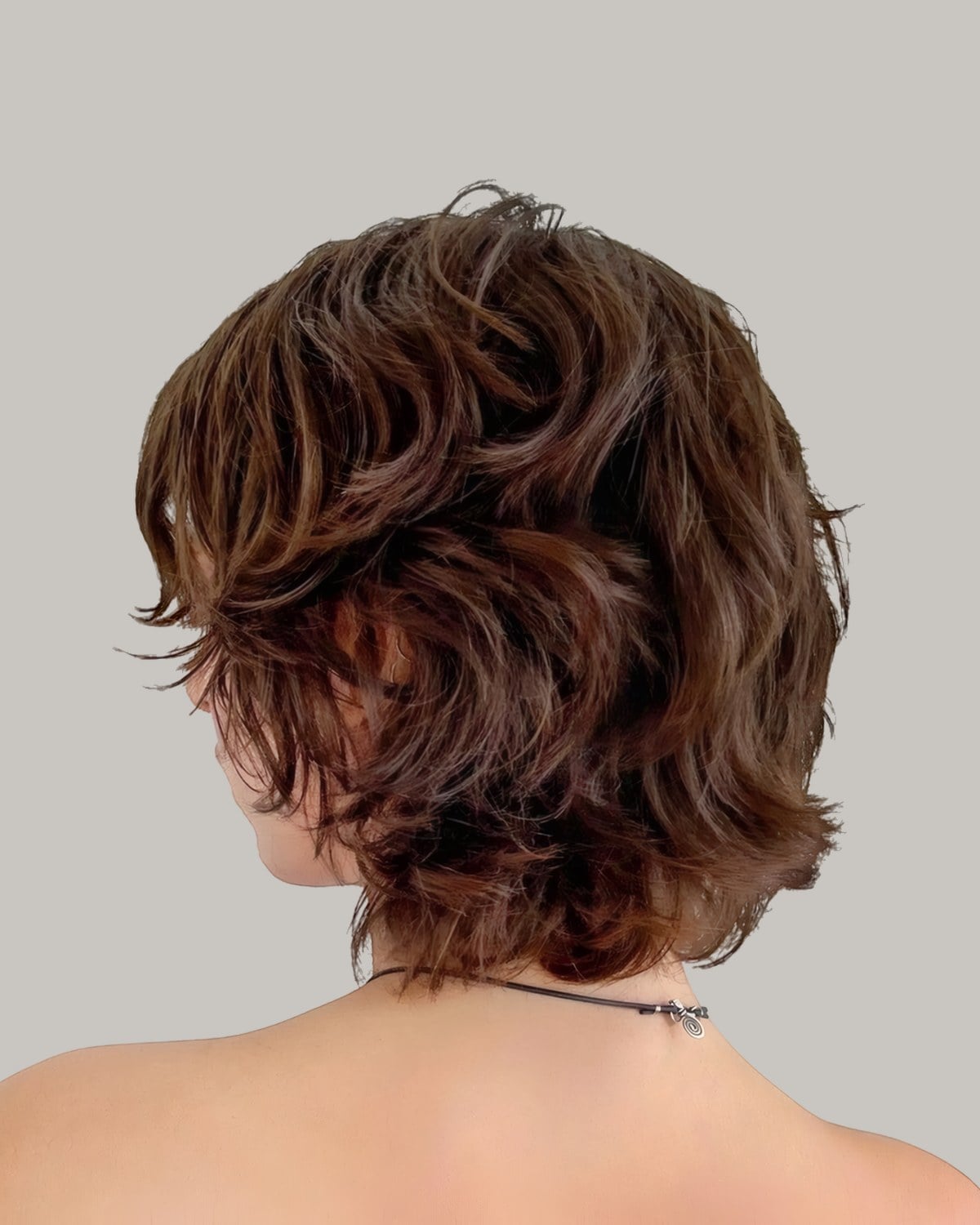 Back view of a short, wavy brown shag above bare shoulders