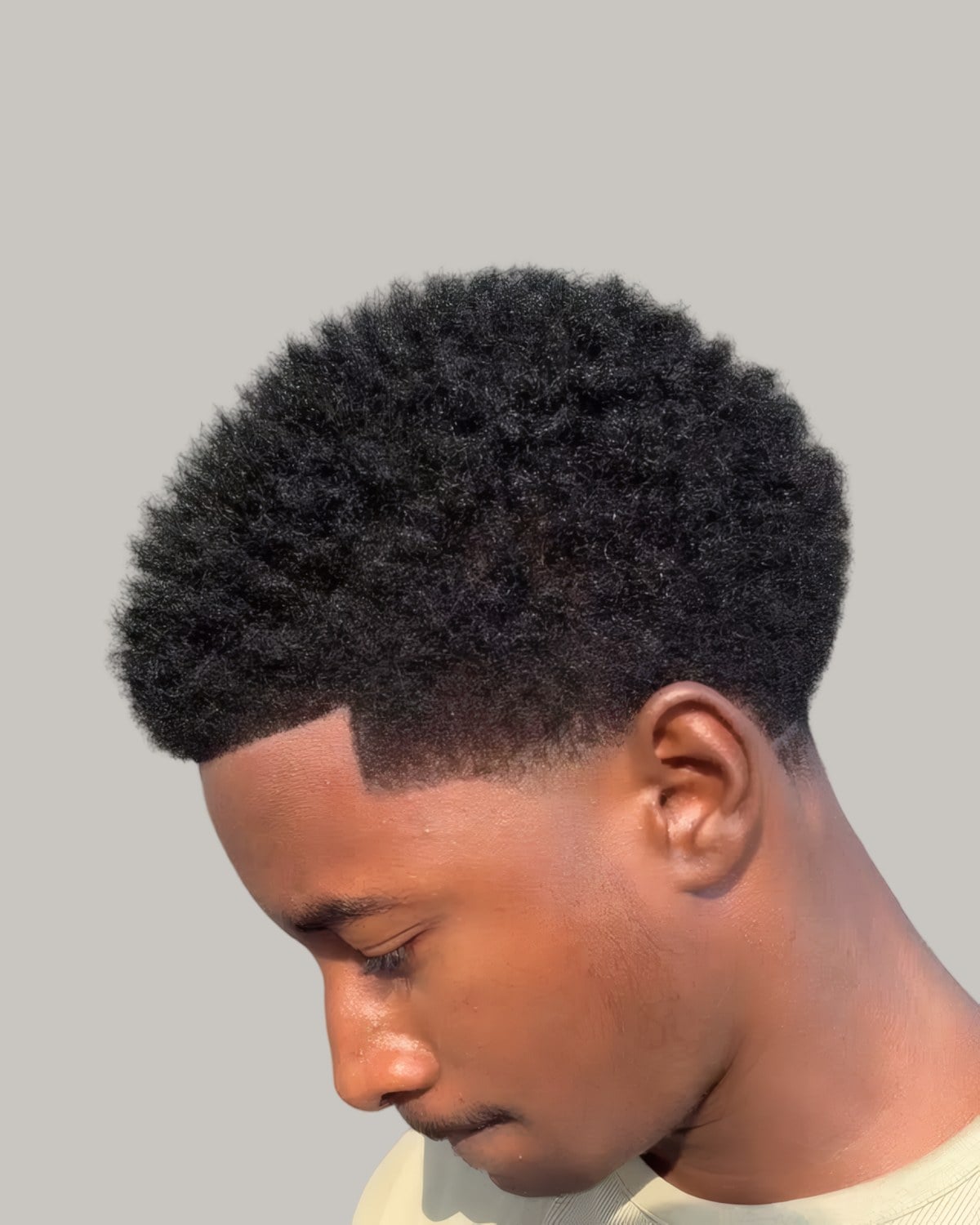 Black man with an Afro taper, looking down