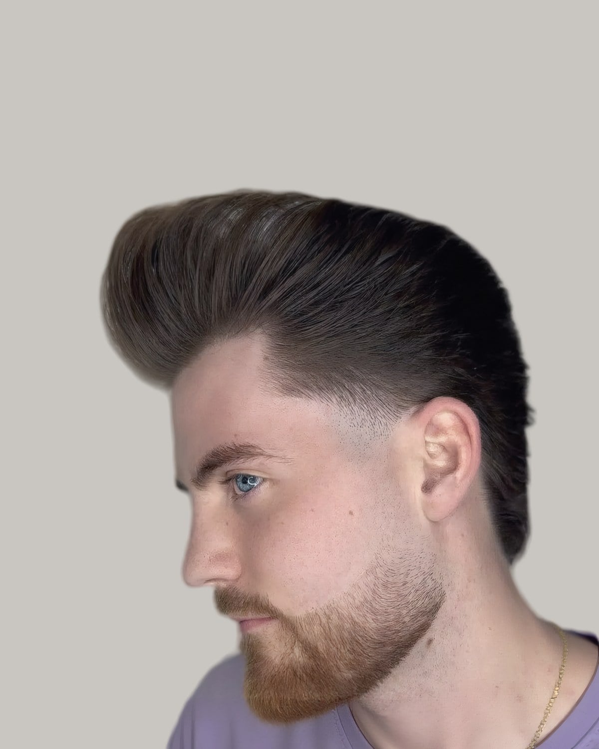 Bearded man with a tall brushed-back pompadour, seen in profile