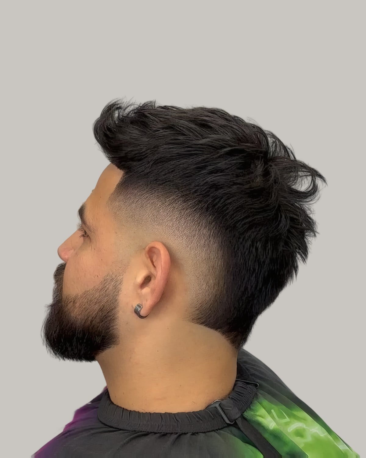 Bearded man with a textured top and a skin fade, seen from behind at an angle