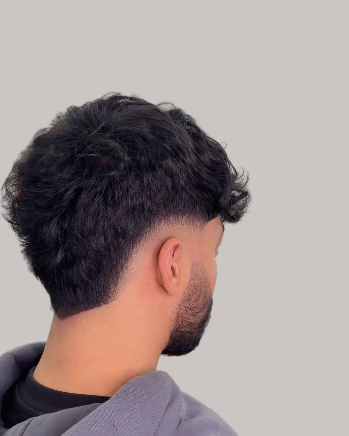 Young man with a textured top and a burst fade, seen in profile