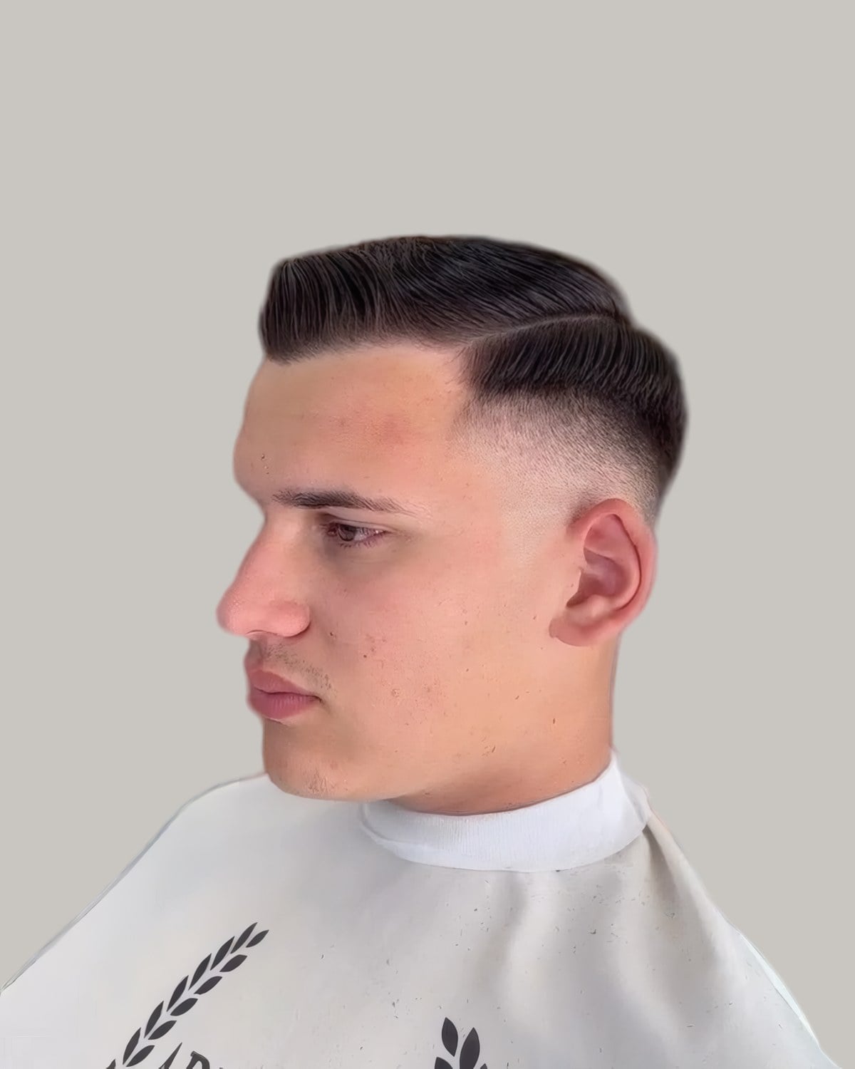 Young man with a side part and a taper, seen in profile