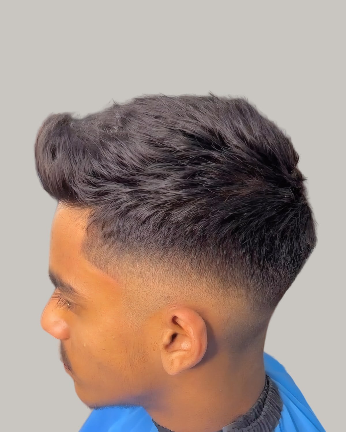 Young man with a brushed-up top and a mid fade, seen in profile
