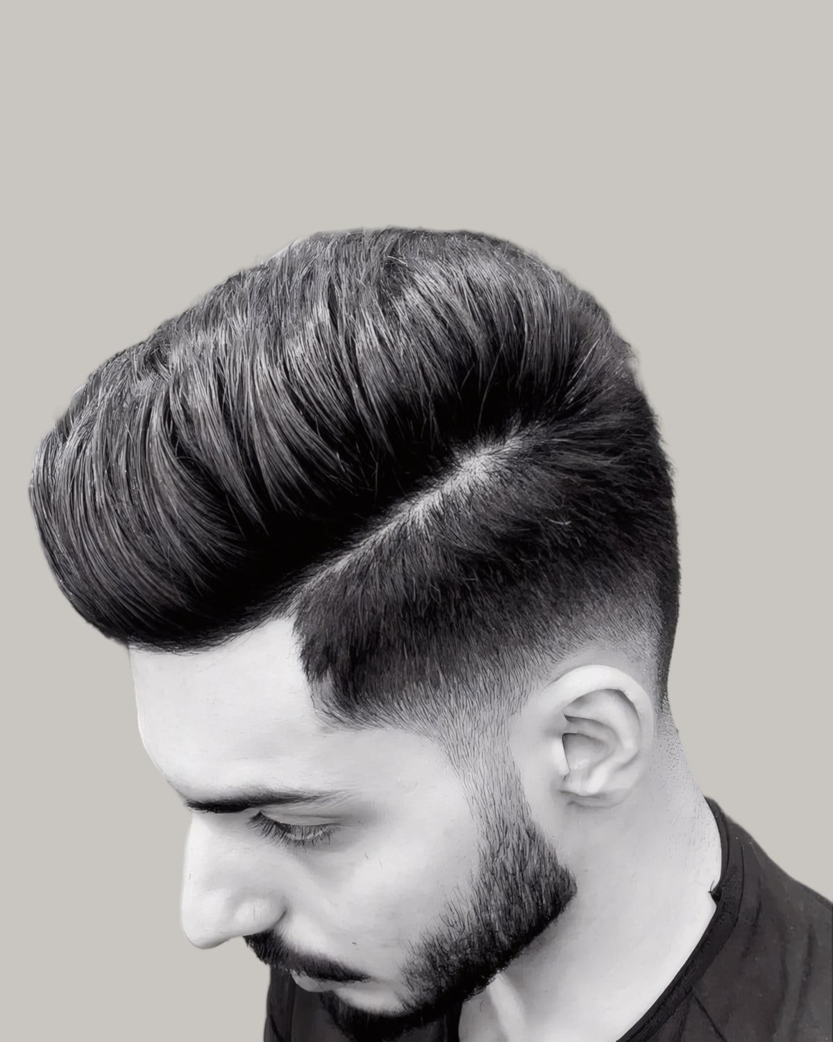 Man with a combed pompadour and a mid fade, in black and white, seen in profile