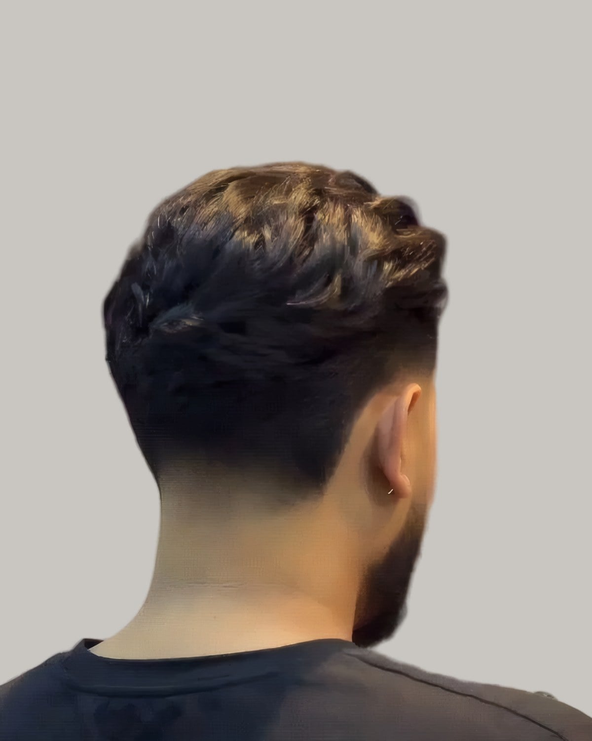 Man with a combed-over top and a taper, seen from behind at an angle