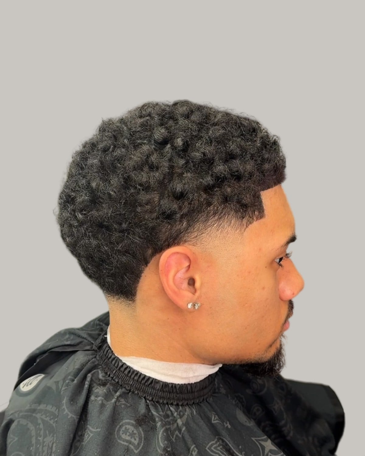 Man with tight curls and a taper, seen in profile