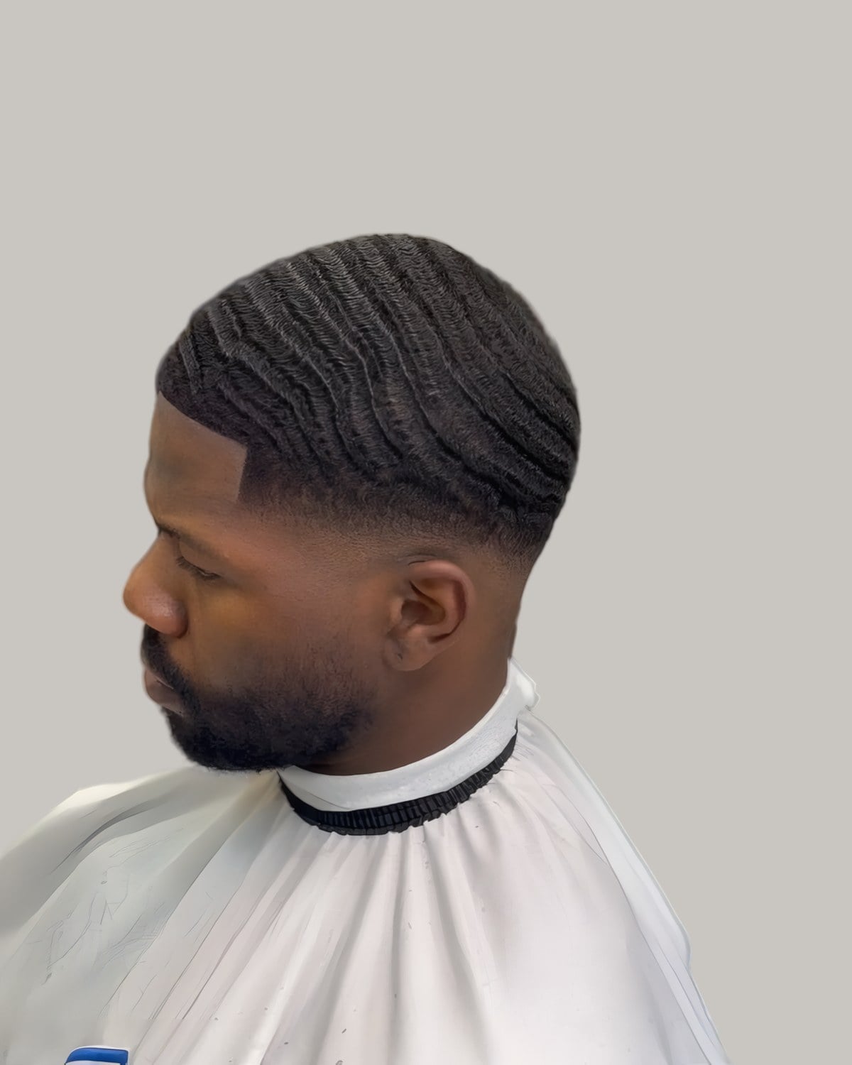 Black man with brushed waves and a taper, seen in profile