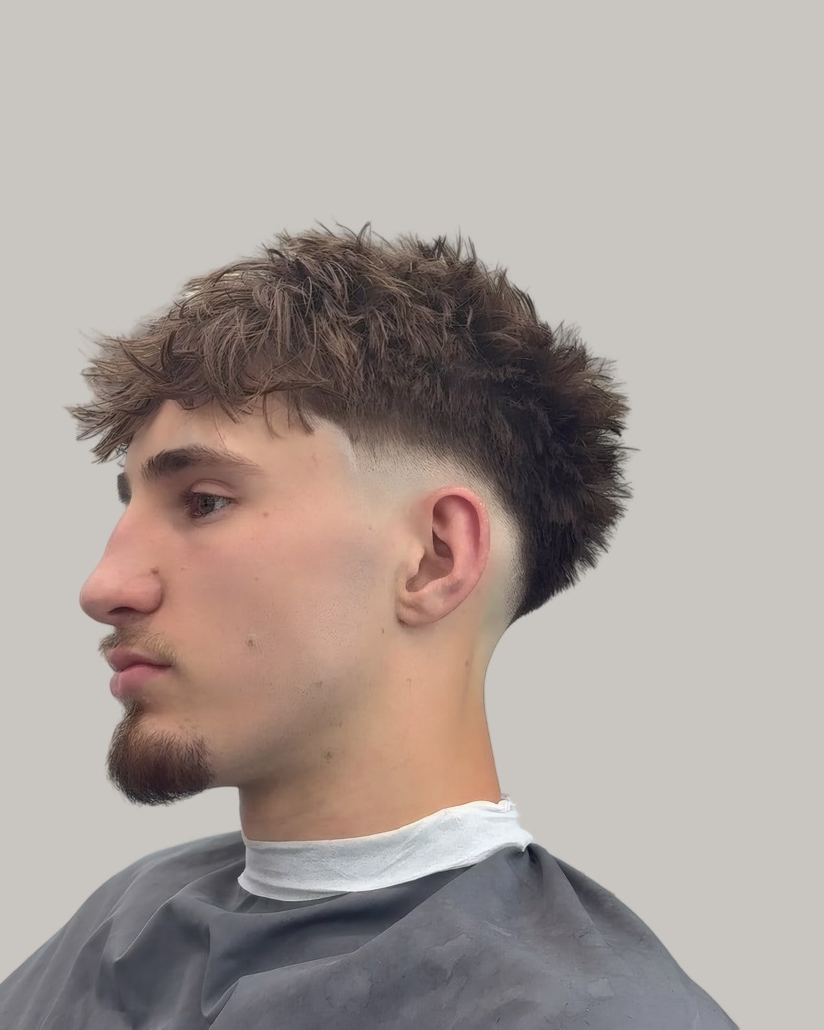 Young man with a textured top and a drop fade, seen in profile
