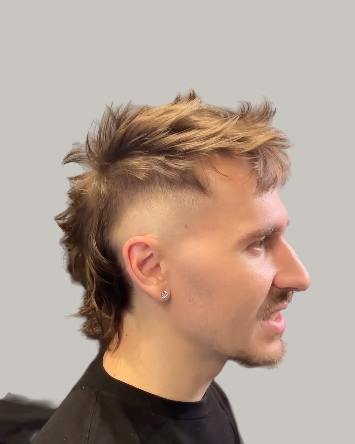 Man with a blond faux hawk and a fade, seen in profile