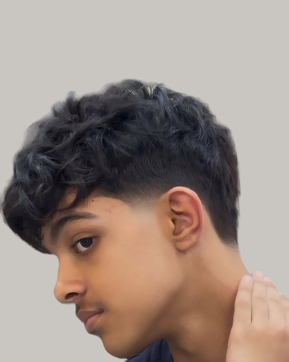 Young man with a wavy top and a low taper, seen in profile