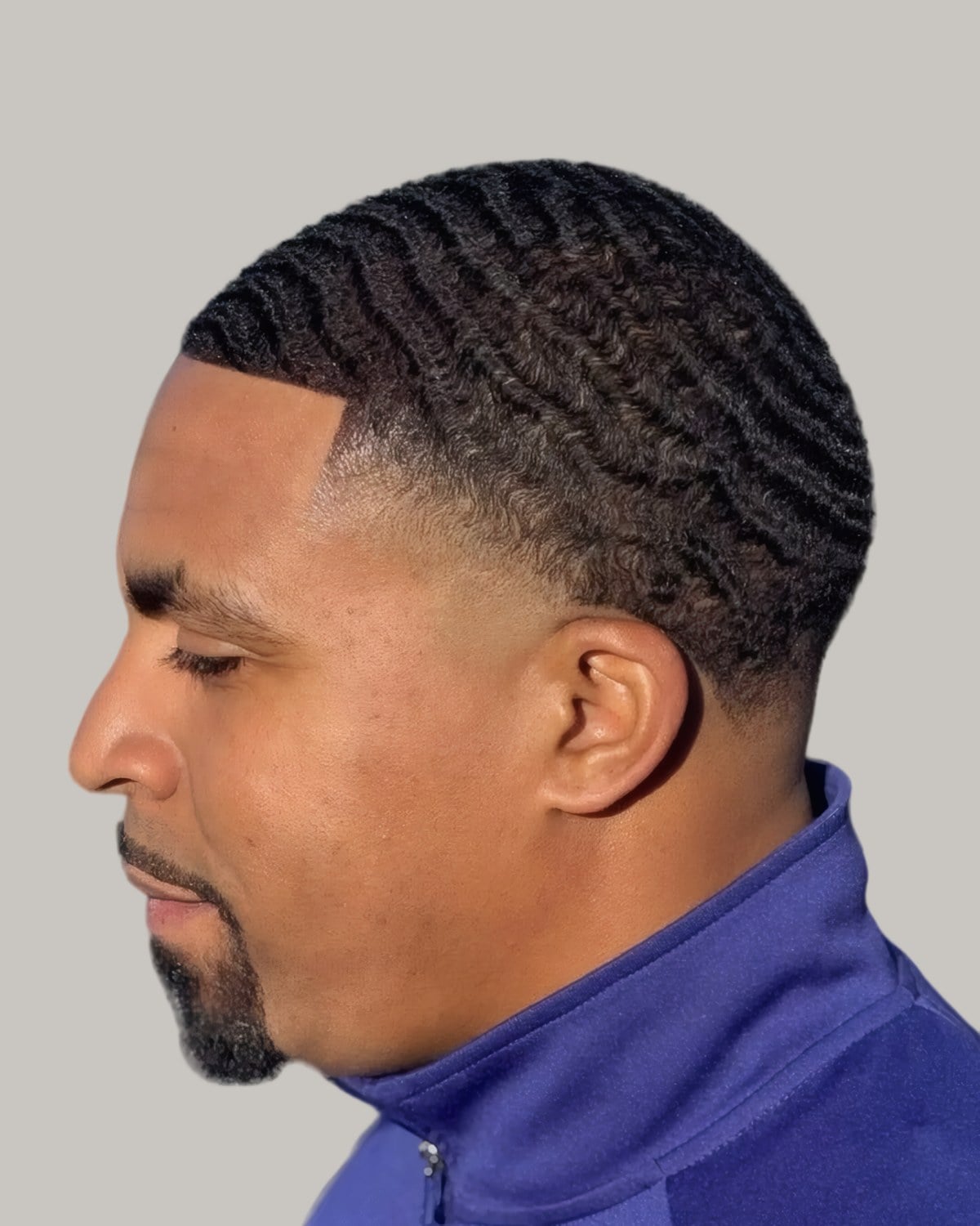 Bearded Black man with 360 waves and a low taper, seen in profile