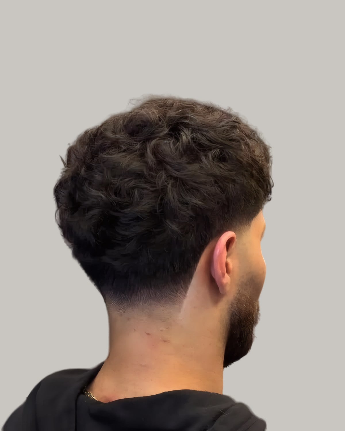Man with a fluffy top and a low taper at the nape, seen from behind