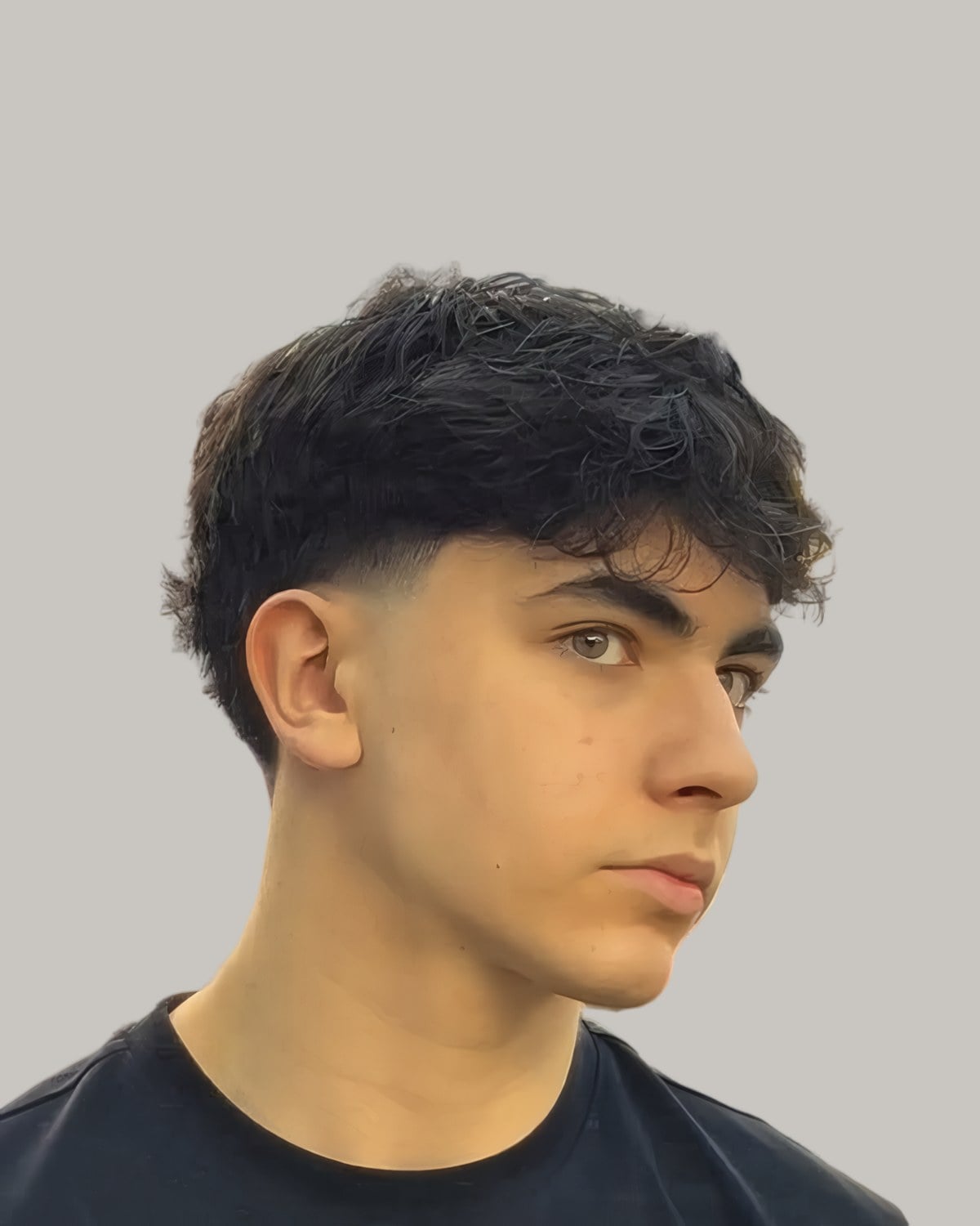 Young man with a dark textured fringe, seen at an angle