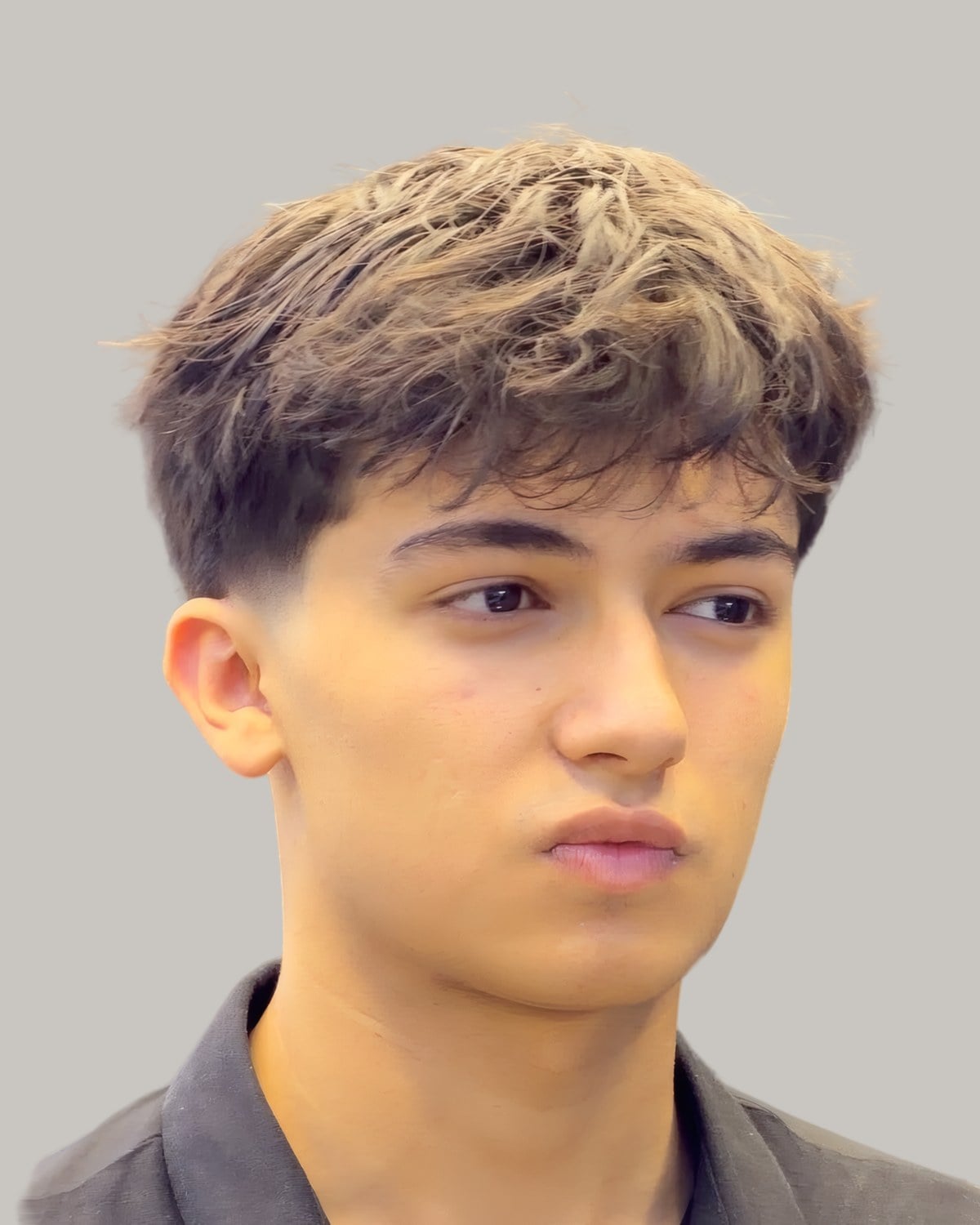 Young man with a textured fringe with lighter tips, seen from the front