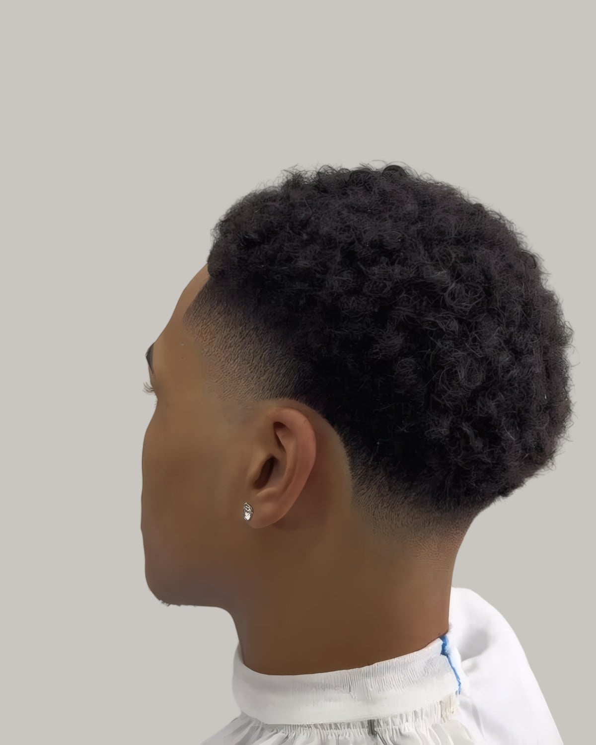 Man with a curly top and a mid taper, seen from behind at an angle