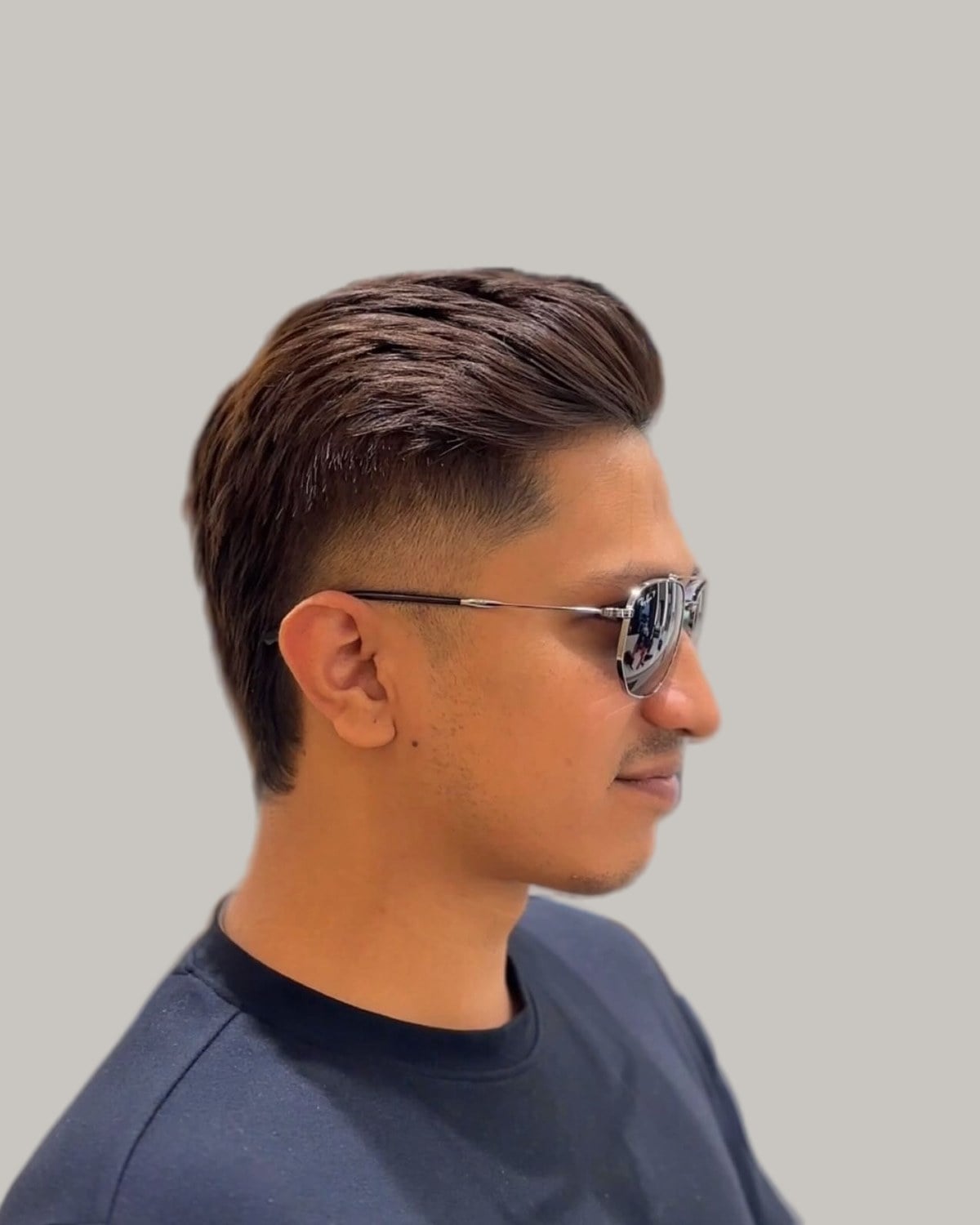 Man in sunglasses with a pompadour and a fade, seen in profile