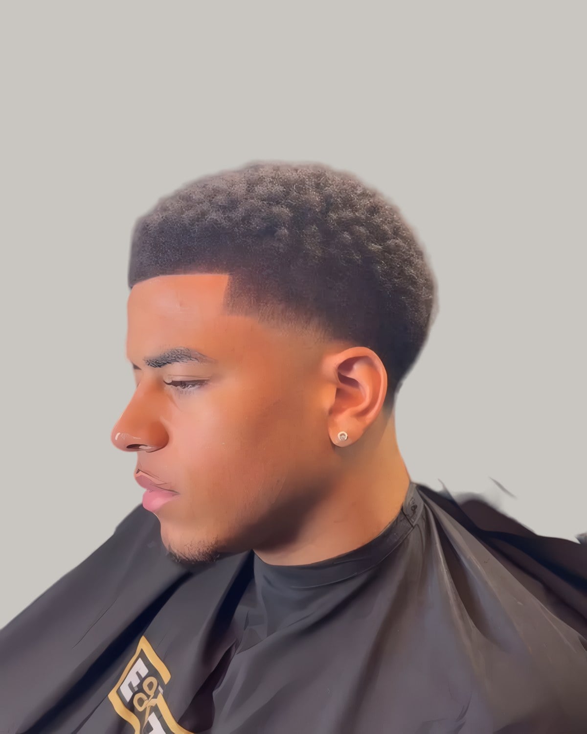 Black man with a curly top and a taper fade, seen in profile