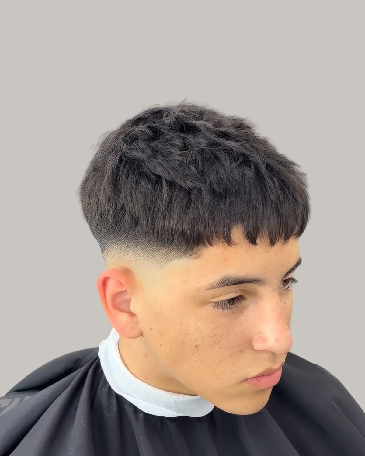 Young man with a textured crop and a low fade, seen at an angle