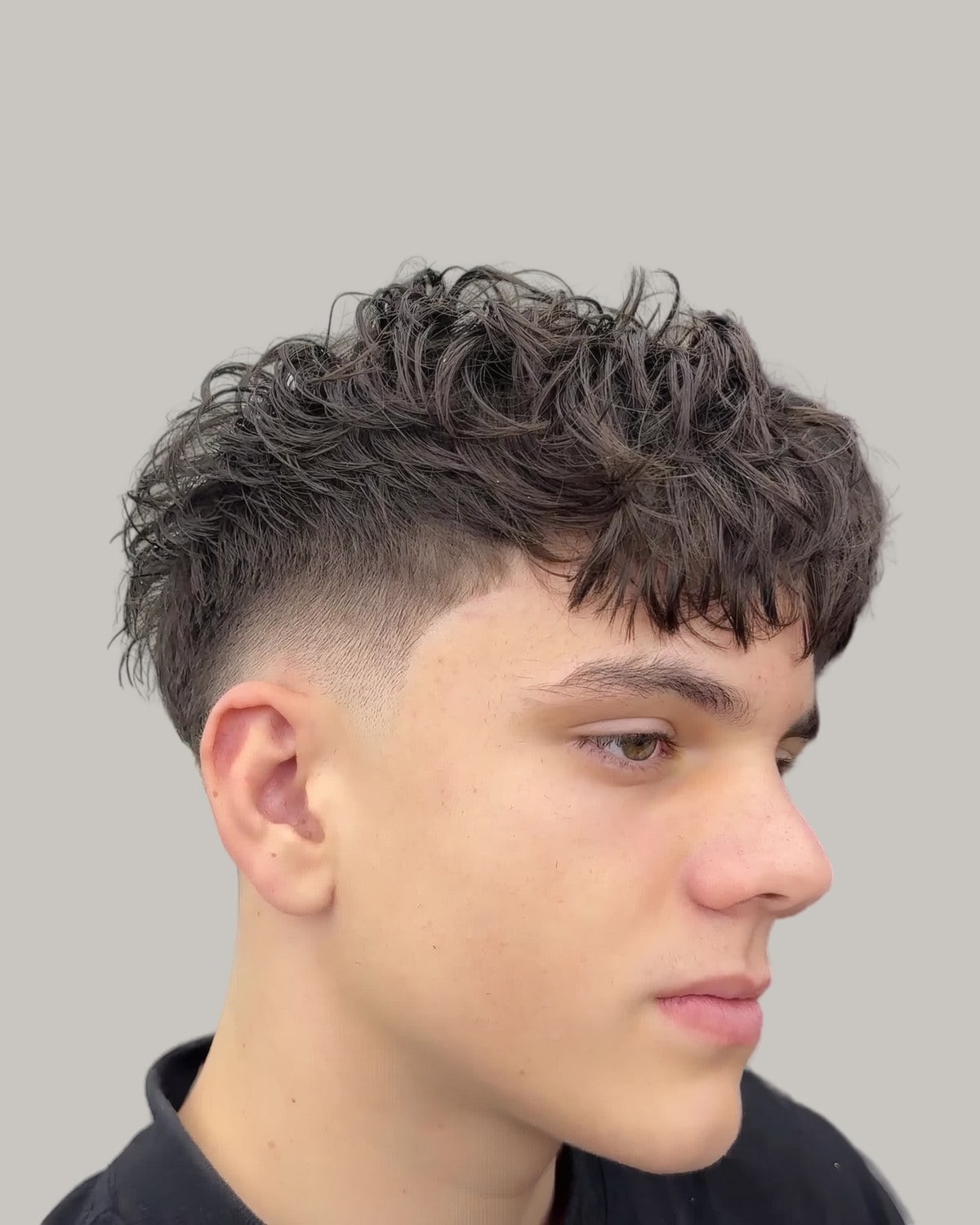 Young man with a curly textured crop and a mid skin fade