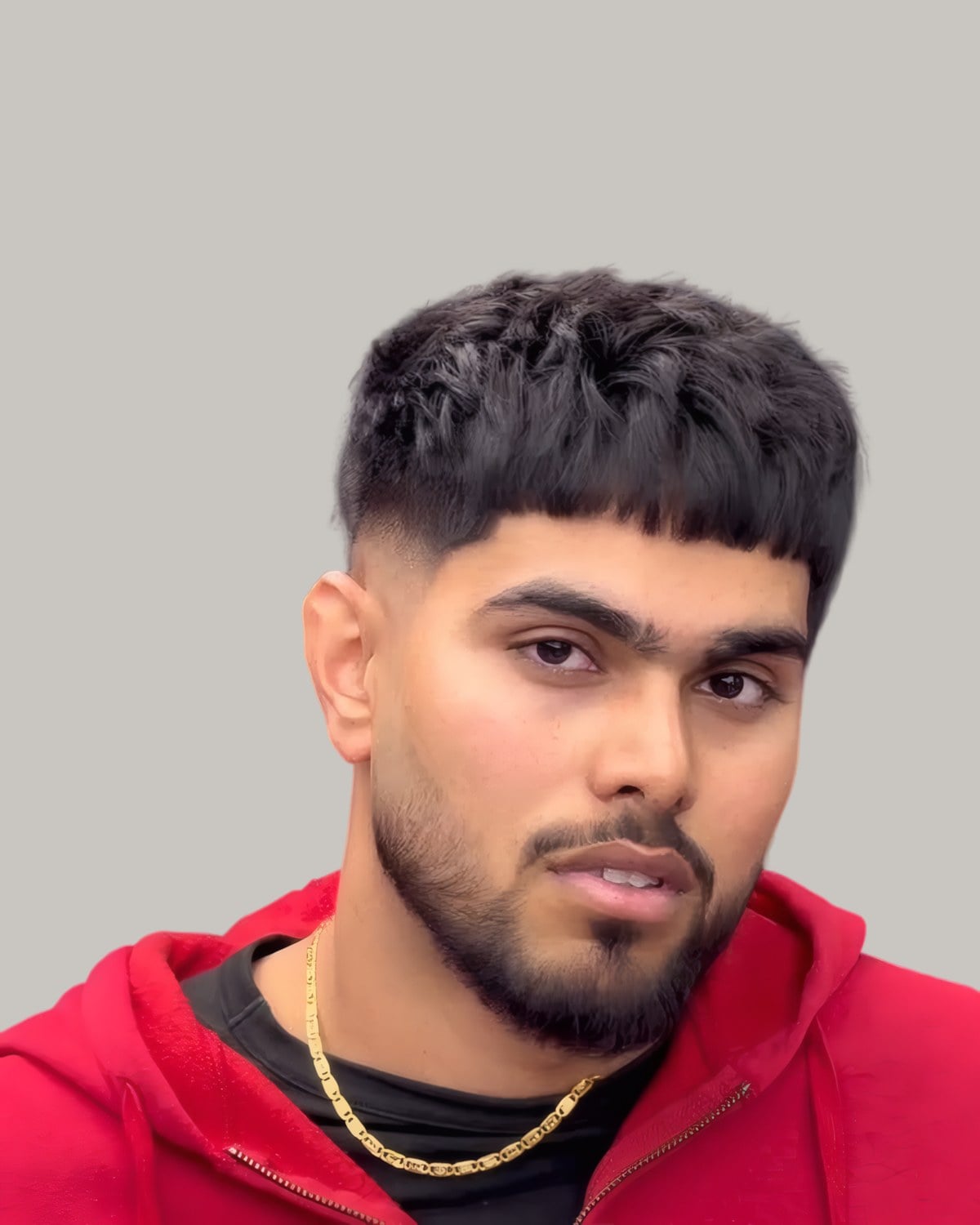 Man with a messy textured crop, a drop fade and a short beard, in a red hoodie
