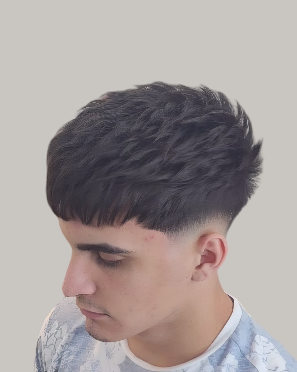Young man with a spiky French crop and a skin fade, looking down