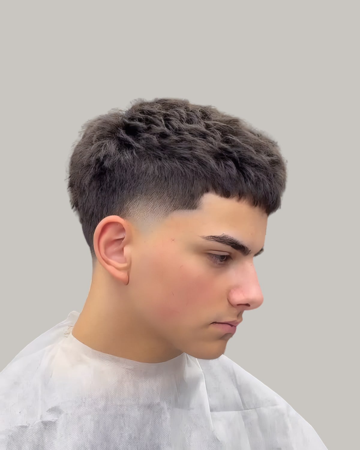 Young man with a dark textured crop, a blunt fringe and a high taper